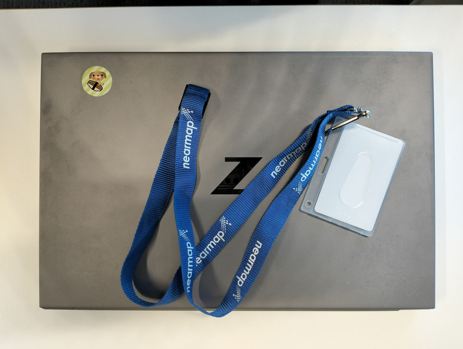 Laptop, with an access pass attached to a Nearmap lanyard on top of it.